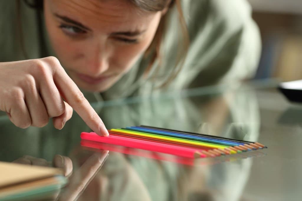 Person carefully arranging coloured pencils