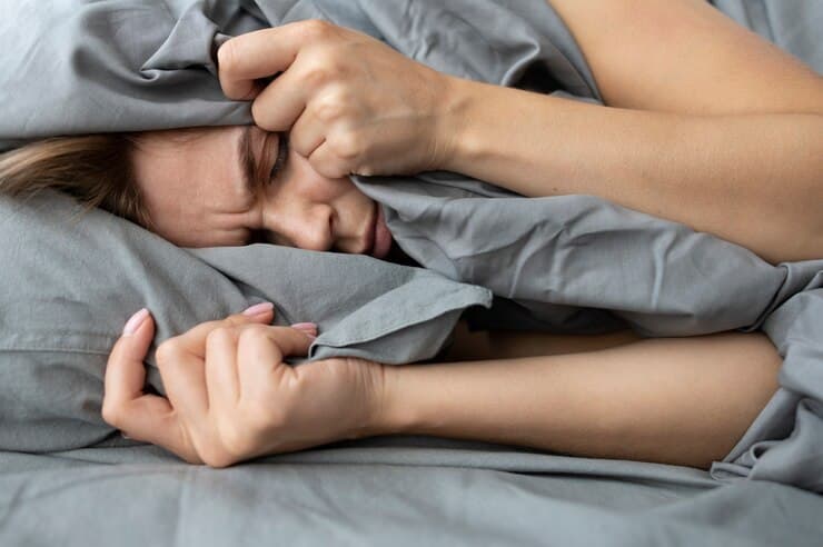 Person lying awake in bed with difficulty sleeping